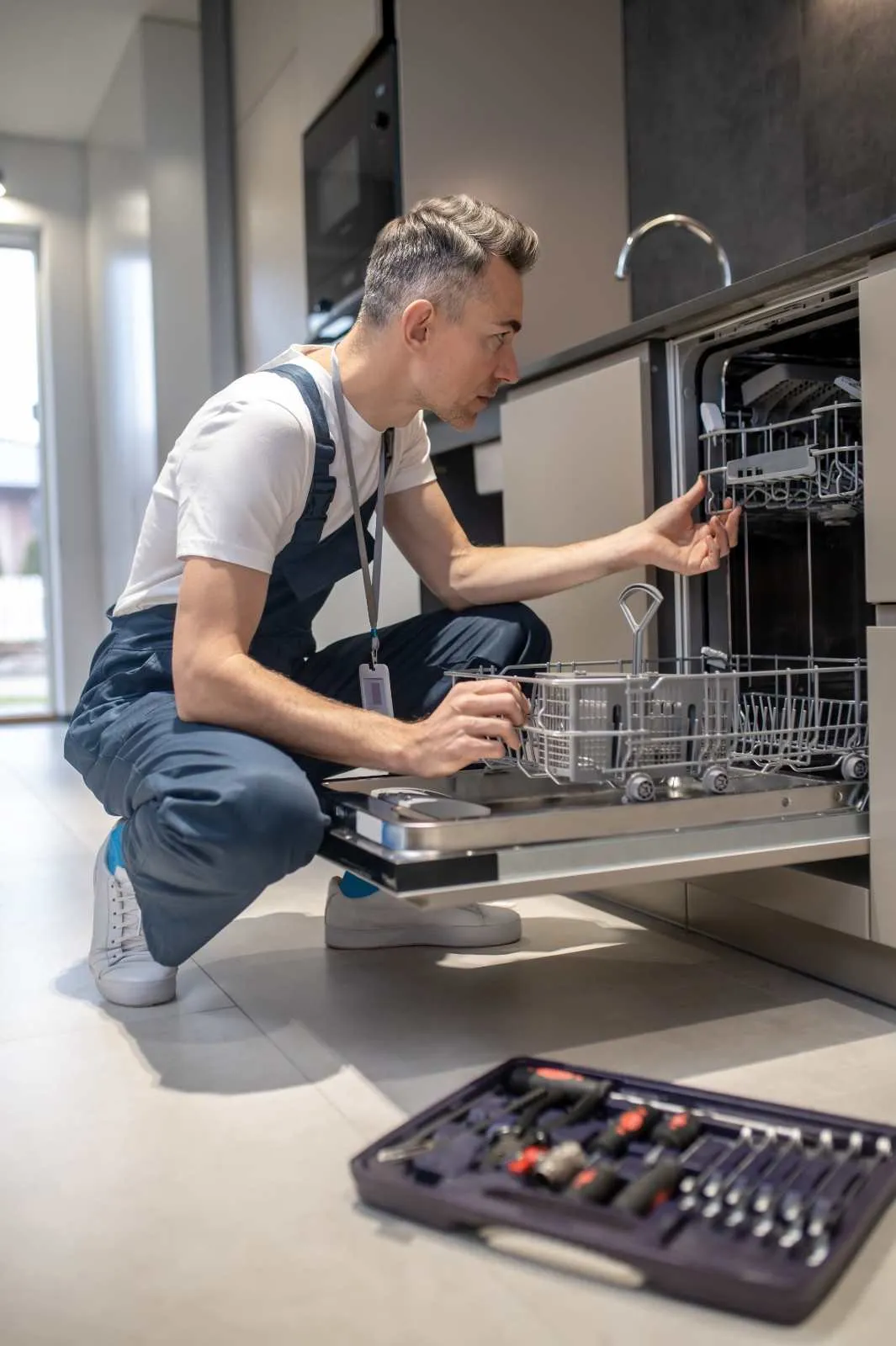 Technician checking a dishwasher in a home kitchen